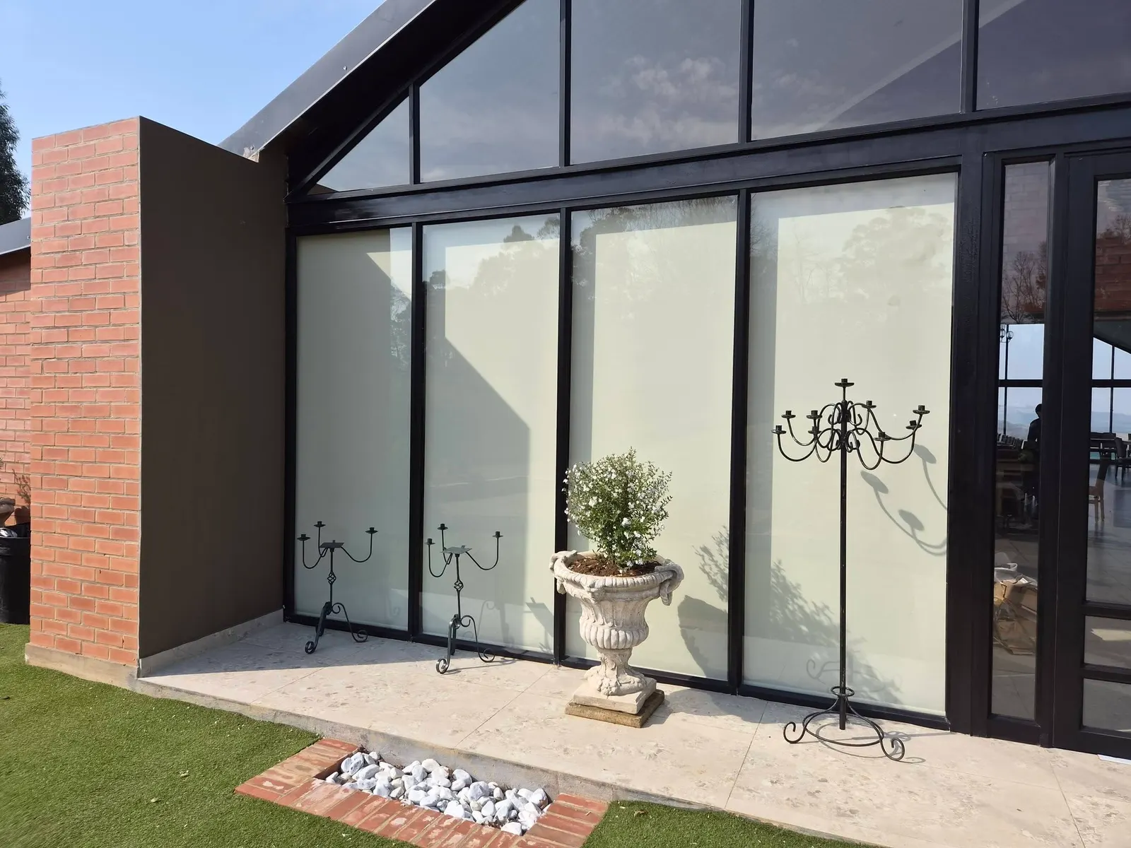 Exterior view of roller blinds fitted to floor-to-ceiling glass on a gable-style venue
